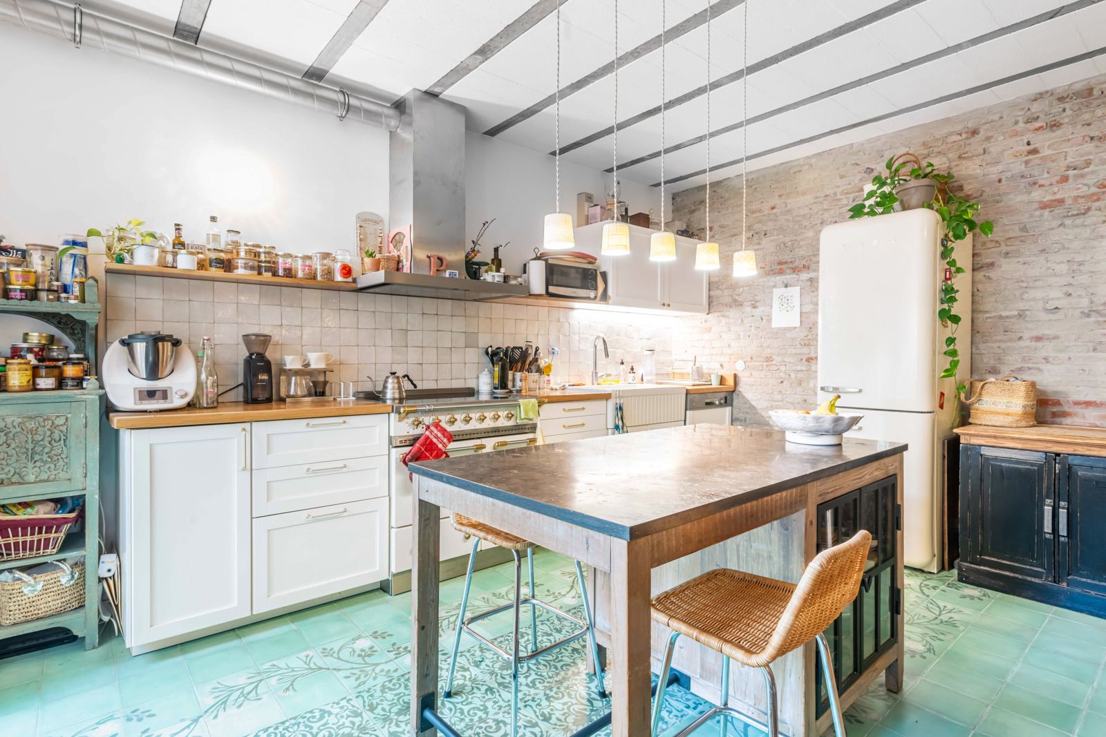 Cuisine avec piano Lacanche, mur de briques, carreaux de ciment et suspensions