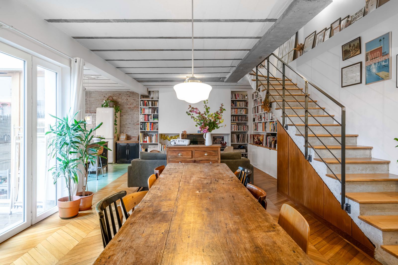 La grande table en bois, chaises dépareillées et escalier