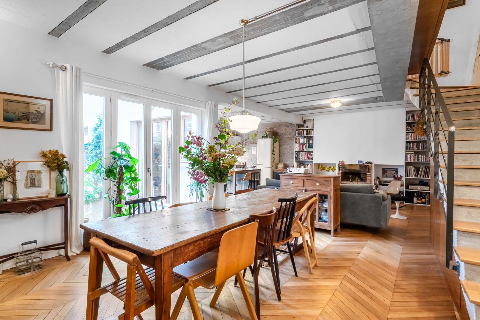 Grande table en bois devant les baies vitrées donnant sur la terrasse
